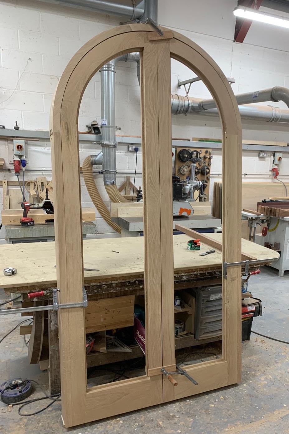 A pair of bespoke arched oak double doors clamped mid-assembly in the workshop