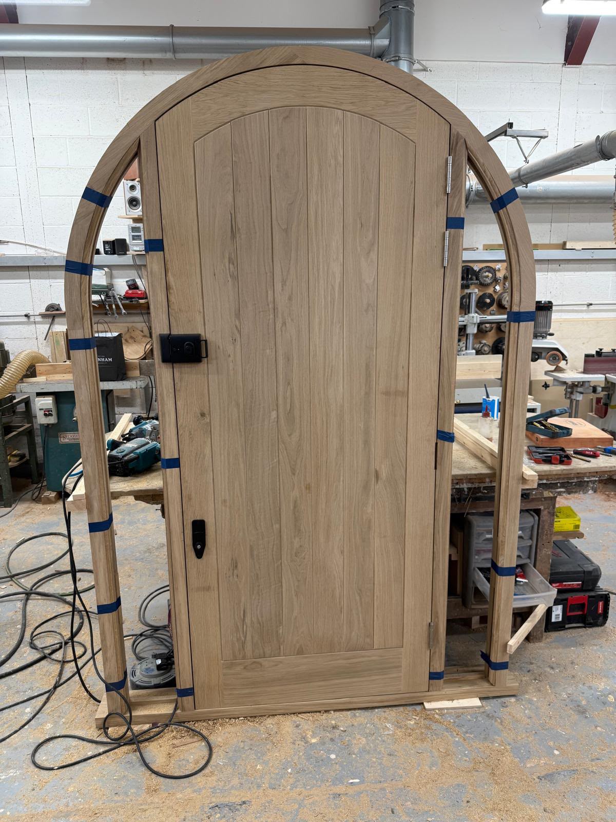 A solid oak arched door with black hand-forged ironmongery
