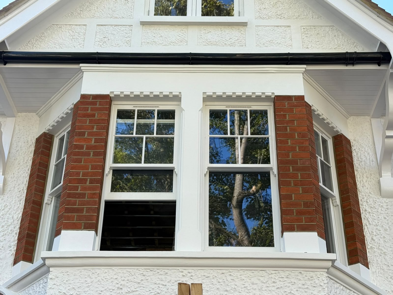 A pair of newly installed timber sash windows in a red-brick bay