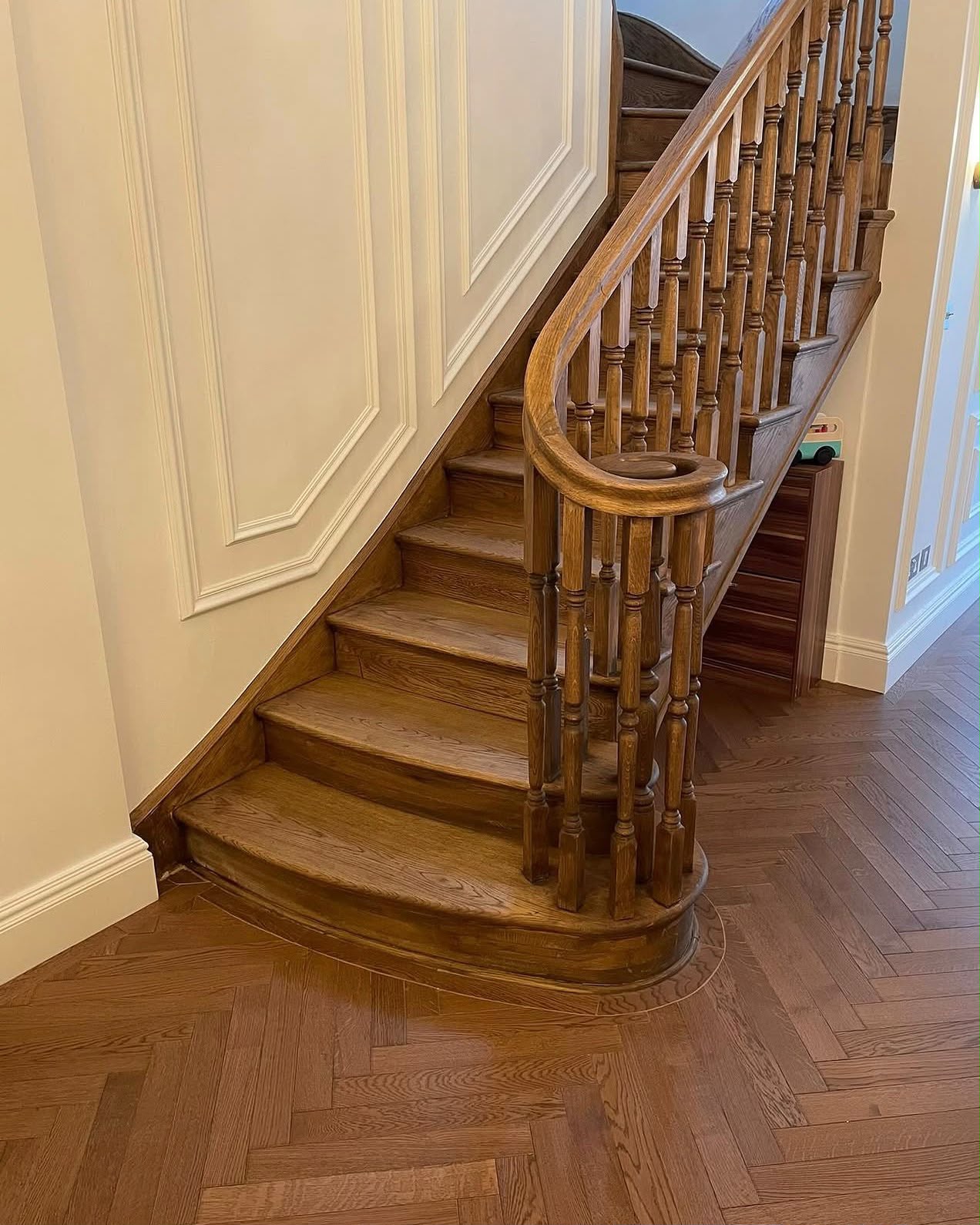 A curved bullnose oak staircase with turned balusters and herringbone flooring