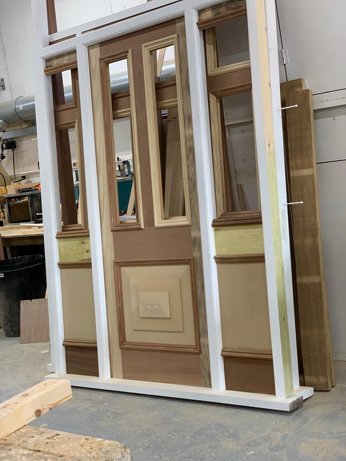 A raised-panel front door and glazed sidelight under construction