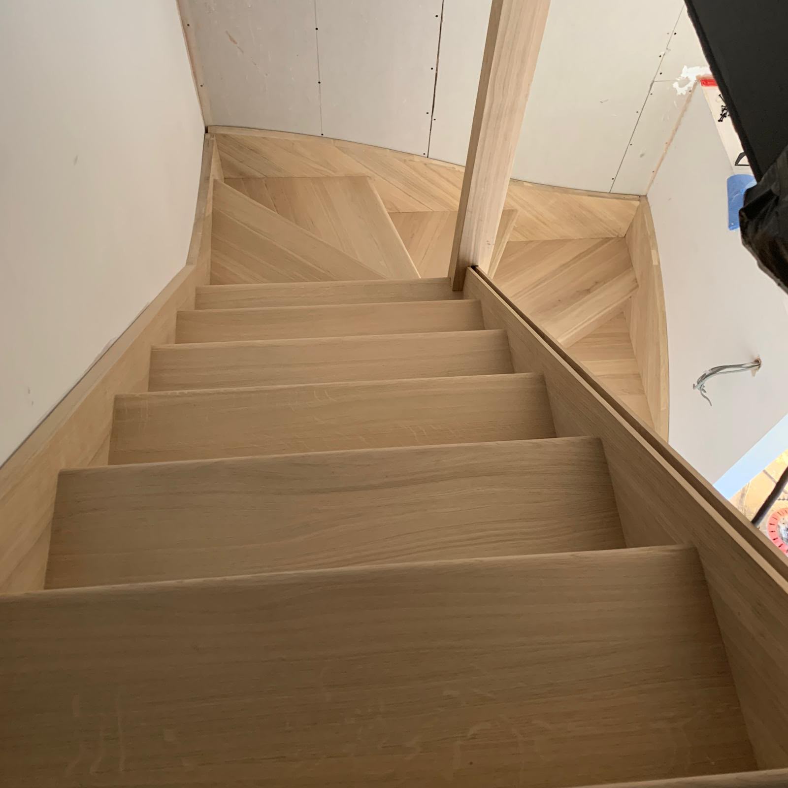 A curved staircase under construction, showing the timber joinery before finishing